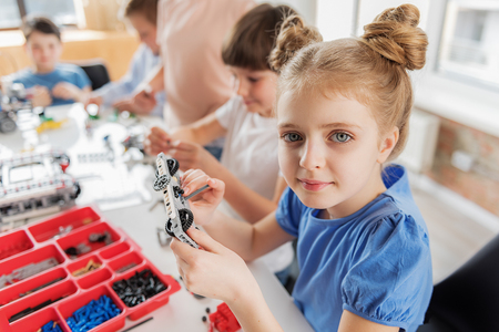 Attentive smiling girl keeping detailの写真素材