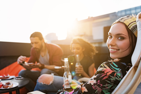 Cheerful young people relaxing on roof with foodの写真素材