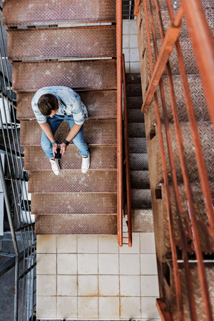 Stylish guy using smartphone on stairsの写真素材