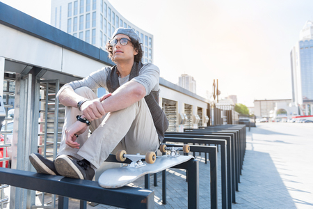 Stylish pensive young guy resting outdoorsの写真素材