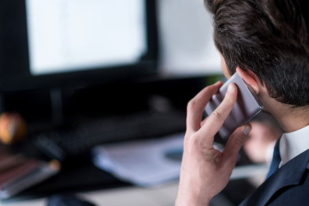 Confident young employee is calling by phoneの写真素材