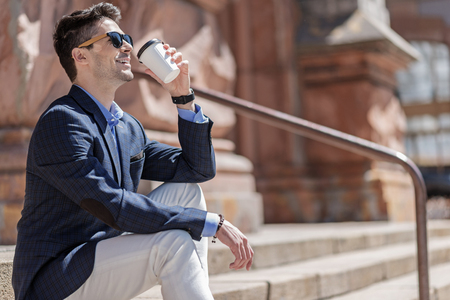 Cheerful man drinking beverage outdoorの写真素材