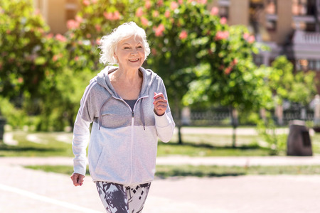 Joyful old pretty woman doing morning exerciseの写真素材