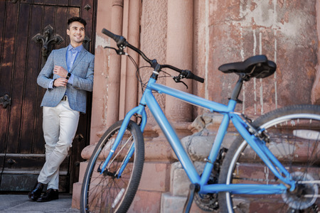 Interested smiling male person glancing up near vehicleの写真素材