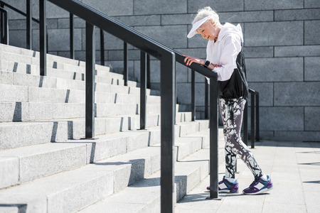 Exhausted old woman having time to rest before raising upstairsの写真素材