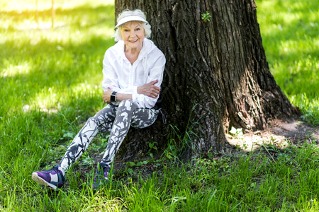 Cheery senior slim lady having relaxation after training outsideの写真素材
