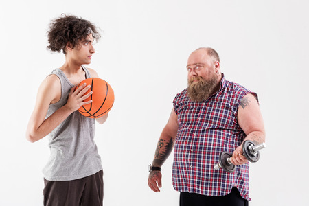 Male thick hipster showing his strength to thin guyの写真素材