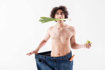 Shocked thin guy eating only fruits and vegetablesの写真素材