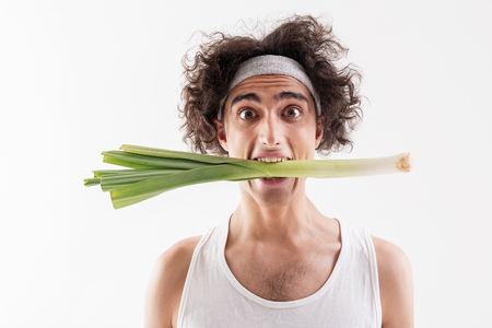 Hungry skinny guy eating healthy onionの写真素材