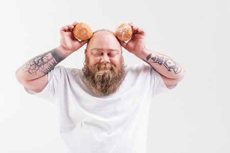 Happy thick guy holding two doughnutsの写真素材