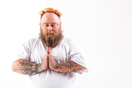 Calm male fatso praying about sausagesの写真素材