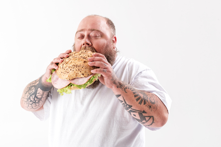 Hungry fat man eating sandwich with appetiteの写真素材