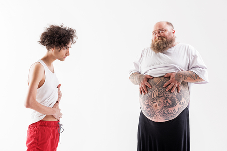 Male fatty boasting of his tummy to skinny guyの写真素材