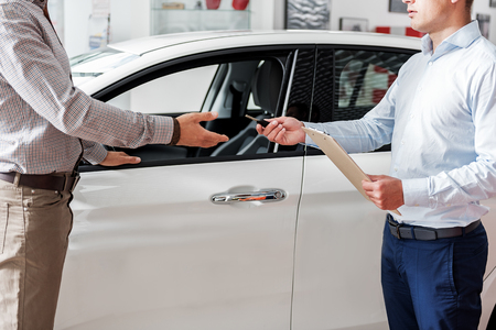 Man taking remote control from serious salesmanの写真素材