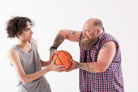 Aggressive thick man bullying young slim guyの写真素材