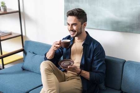 Happy youthful guy having leisure time in his apartmentの写真素材