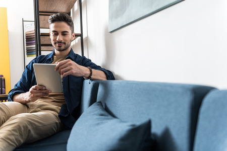 Happy youthful guy resting at home using modern technologies