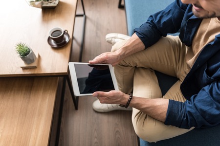 Cheerful guy having fun using gadget in his roomの写真素材