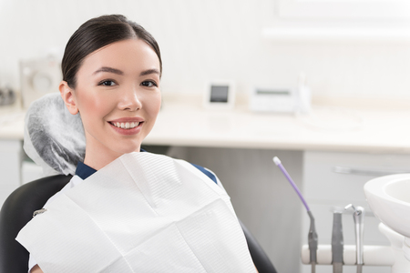 Cheerful girl situating on seat in stomatologyの写真素材