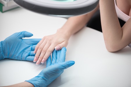 Beautician is holding hands of young womanの写真素材