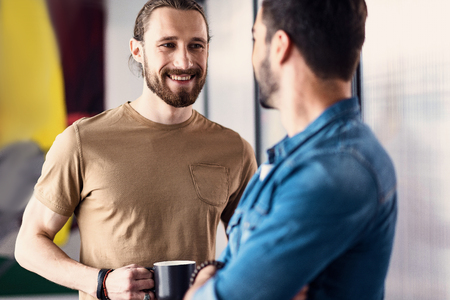 Joyous bearded man talking to coworkerの写真素材