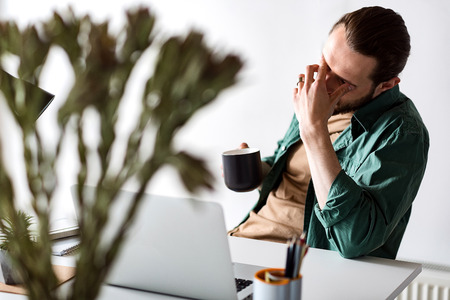 Exhausted man working in officeの写真素材