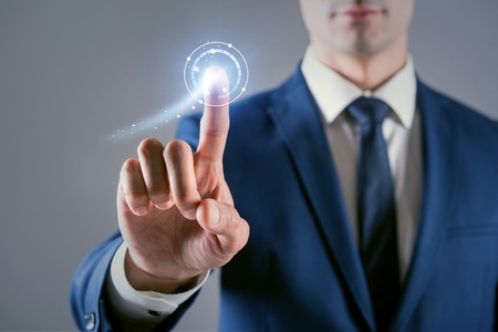 Cyberspace and virtual reality. Close-up of hand of pleasant businessman which is pressing digital button of modern touch screenの写真素材