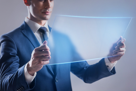 Elegant guy is holding translucent tabletの写真素材