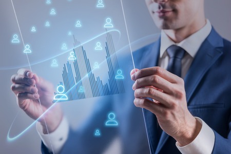 Business technology internet and communication computer network concept. Pleasant young businessman is holding transparent screen of future and working with itの写真素材