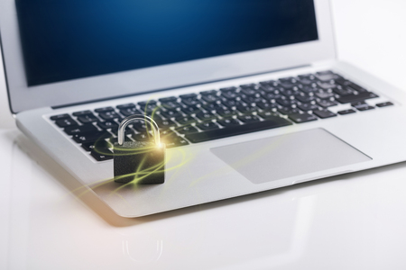 Protection data concept. Close up of metal padlock with yellow light is on keyboard of modern laptop. Selective focus. Copy space in the right sideの写真素材