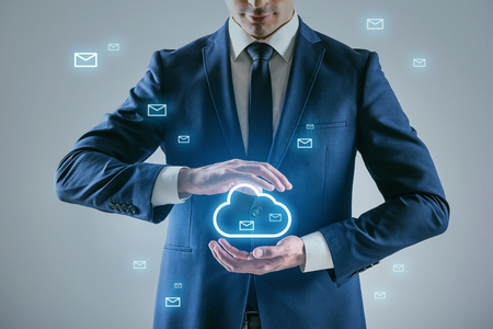 Connect to information system. Businessman in blue suit is standing around swarm of emails shaping virtual cloud at center of wireless computing networkの写真素材