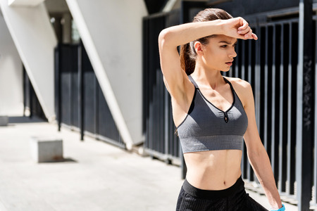 Exhausted young woman making break after workoutの写真素材