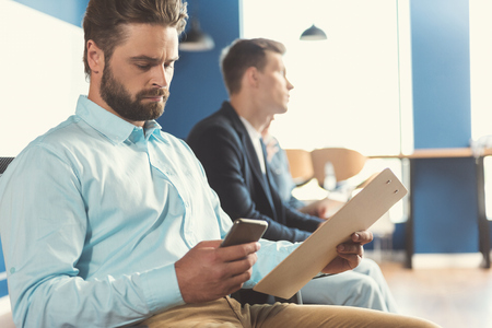Concentrated guy with beard waiting for job consultation in officeの写真素材