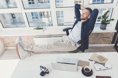 Confident pleasant guy is resting in officeの写真素材