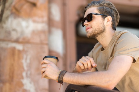 Serious youthful guy with beard resting outdoorの写真素材