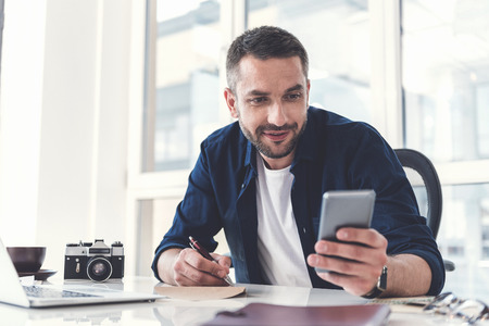 Joyful adult guy is checking data infoの写真素材
