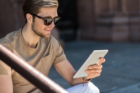 Happy youthful bearded guy having rest in city outdoorの写真素材