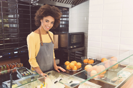 Joyful african young woman laboring in vegetarian shop with pleasureの写真素材