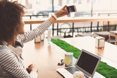 Joyful young woman is making photo of herself