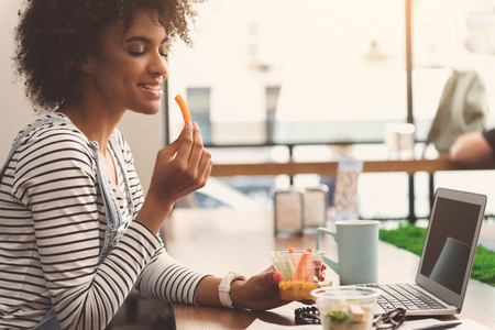 Pleasant charming girl is enjoying her lunchの写真素材