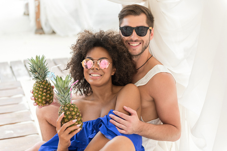Jolly youthful couple enjoying summer drinks on resortの写真素材