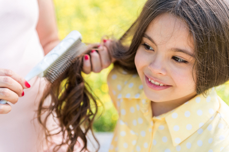 Expectant mother combing hair of her kidの写真素材