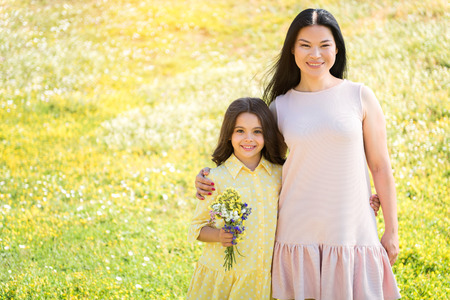 Friendly parent and child hugging on grasslandの写真素材