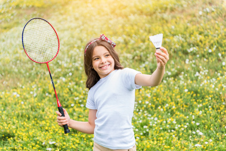 Excited female kid playing tennis on fieldの写真素材