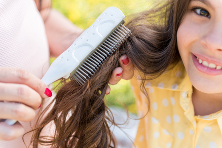 Pregnant woman doing hairstyle for her little daughterの写真素材
