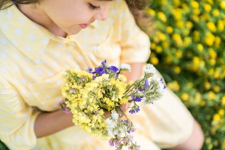 Cute little kid enjoying beauty of wildflowersの写真素材