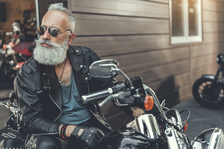 Serious bearded old man on motorbikeの写真素材