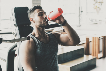 Serious unshaven athlete tasting beverage in gymの写真素材