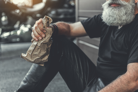 Old bearded man keeping bottle of beerの写真素材