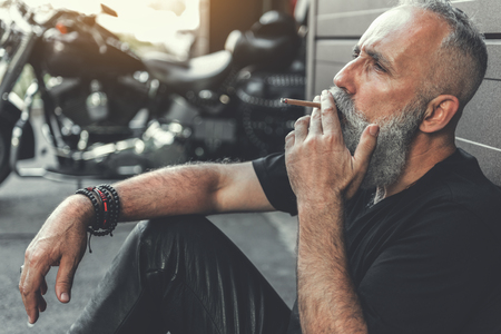 Tired mature bearded man smokingの写真素材